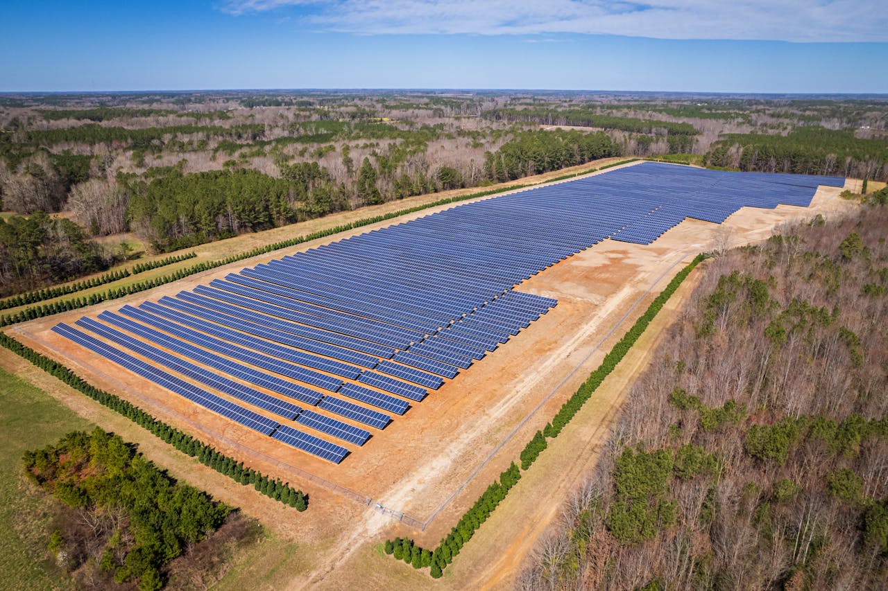 services-02 Aerial drone shot of a large solar panel farm in a rural area surrounded by forests in North Carolina.